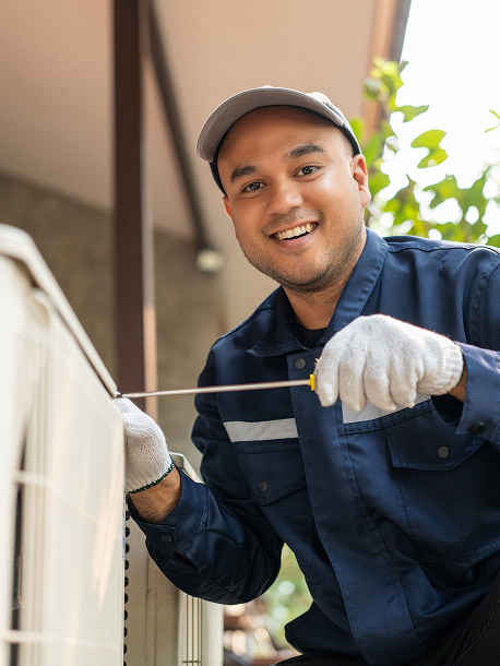 Brookside hvac technician repairing hvac unit in backyard of home wearing blue suit and smiling